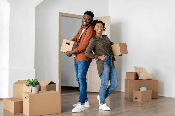 Joyful Black Spouses Holding Cardboard Moving Boxes In New House — 스톡 사진