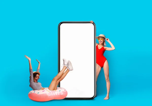Two Cheerful Excited Multiethnic Women Wearing Summer Outfits Posing Near Blank Smartphone — Stockfoto