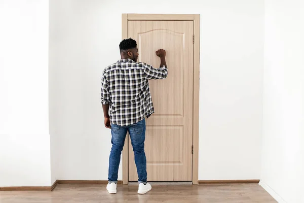 Back View Of African American Man Knocking At Door Indoor — Stockfoto