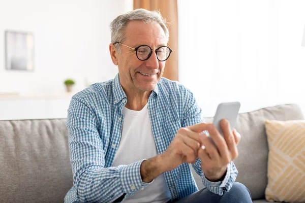 Portrait of mature man using smartphone sitting on couch — Stock Fotó