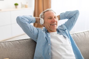 Heyecanlı olgun bir adam evde oturup müzik dinliyor.