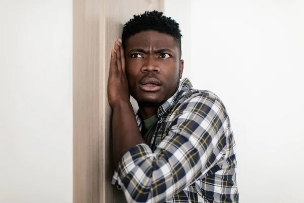 Curious Black Guy Listening Putting Ear To Door At Home — Fotografia de Stock