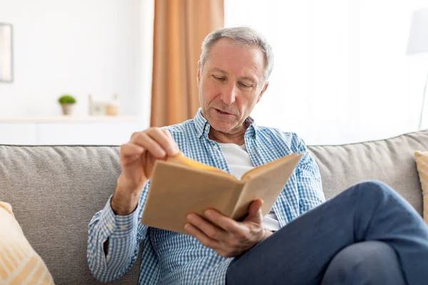 Porträt eines reifen Mannes, der zu Hause Buch liest — Stockfoto