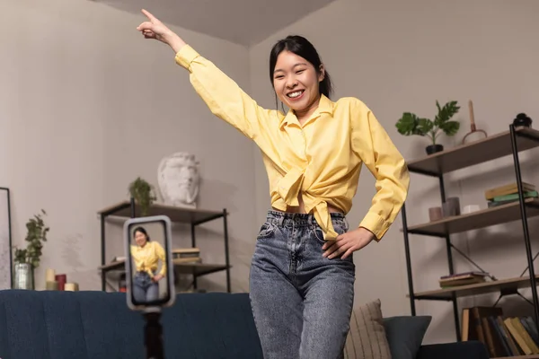 Cheerful Asian woman dancing at camera filming video on cellphone — Photo