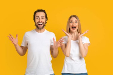 Glad excited millennial caucasian husband and wife in white t-shirts rejoice in victory