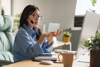 Asian woman using laptop wearing headset making video call