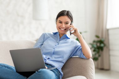 Çinli kadın girişimci, evden çalışıyor, telefonla konuşuyor.
