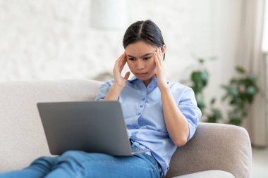 Yorgun Asyalı kadın evden internet üzerinden çalışıyor.