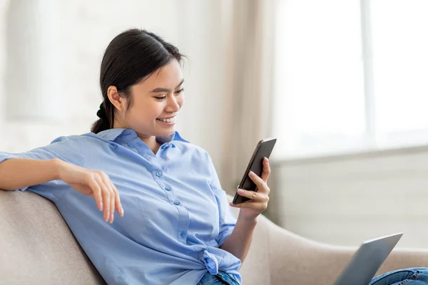 Happy chinese lady using laptop and smartphone at home — Stockfoto