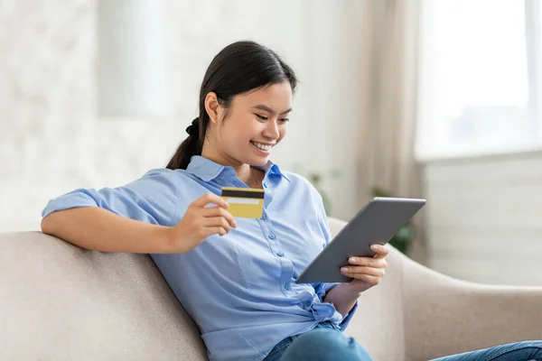 Positive asian woman shopping online, using tablet and credit card — Stock Photo, Image