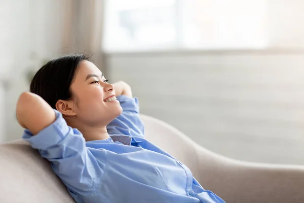 Cute chinese woman resting on sofa at home, copy space — Stockfoto