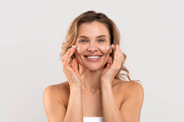 Antiage Treatment. Beautiful Caucasian Woman Applying Moisturizing Cream On Face — Φωτογραφία Αρχείου