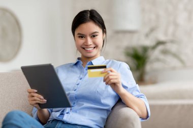 İnternetten alışveriş yapan neşeli Japon kadın kredi kartı öneriyor.