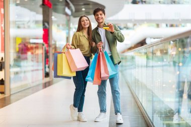 Alışveriş yapan çift alışveriş merkezinde kredi kartı pozu veriyor.