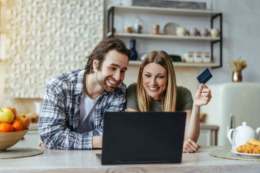 Sakallı ve sarışın bir kadın olan beyaz bir adamın kredi kartı gösterip mutfak iç dizüstü bilgisayarına bakmasına sevindim.