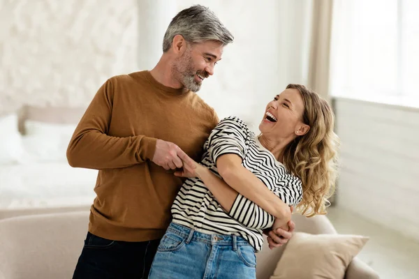 Радісна пара танцює і сміється вдома — стокове фото