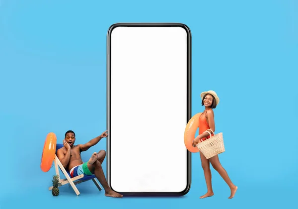 Vacation Offer. Black man and woman wearing swimsuits relaxing near blank smartphone — Stockfoto