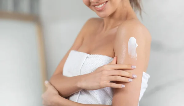 Senhora aplicando creme no ombro hidratando a pele no banheiro, cortado — Fotografia de Stock