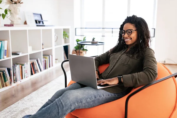 Ritratto di donna nera sorridente che usa il computer portatile a casa — Foto Stock