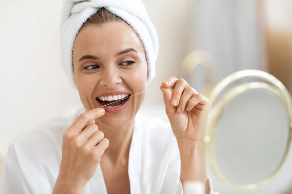 Mujer adulta usando hilo dental, limpiando sus hermosos dientes blancos —  Fotos de Stock