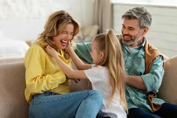 Радісні батьки і дочка розважаються сміючись сидячи вдома — стокове фото