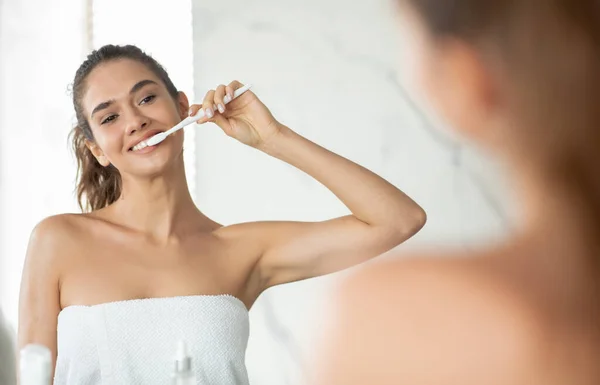 Mulher feliz escovando os dentes cuidando de higiene oral no banheiro — Fotografia de Stock