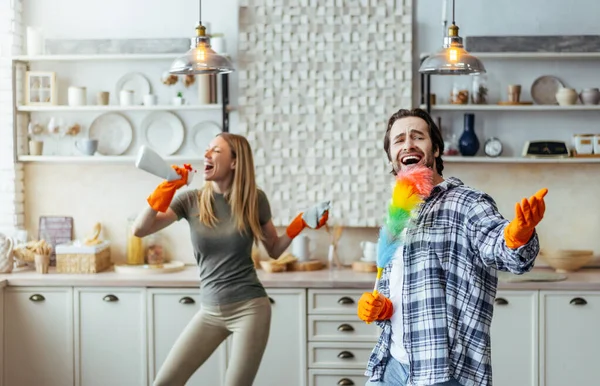 Happy excited man with stubble in rubber gloves and wife with spray sing at imaginary microphone — Stok fotoğraf