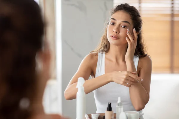 Young Lady Applying Foundation Cream Making Makeup In Bathroom Indoors — стоковое фото