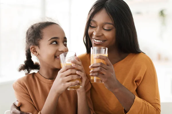 ดํา แม่ และ ลูกสาว กอด ดื่ม ส้ม น้ําผลไม้ในครัว — ภาพถ่ายสต็อก