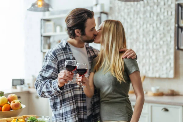 Happy handsome caucasian millennial man with stubble kisses woman blond, cheers with glasses — Stock Photo, Image
