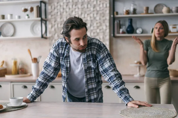 Sad dissatisfied european millennial male with stubble sighs, upset blonde wife screams hasband — Stockfoto