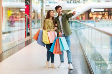 Alışveriş Merkezinde Renkli Poşetli Çift Parmağını İşaret Ediyor