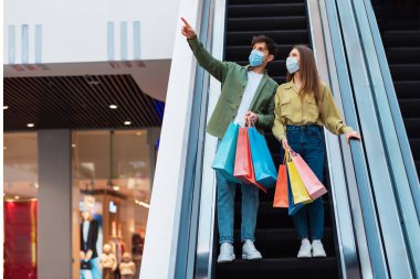 Couple Shopping Pointing Finger Aside In Hypermarket, Wearing Face Masks