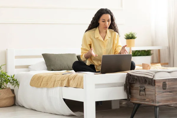 Kvinna med bärbar dator gör videosamtal sitter på sängen — Stockfoto