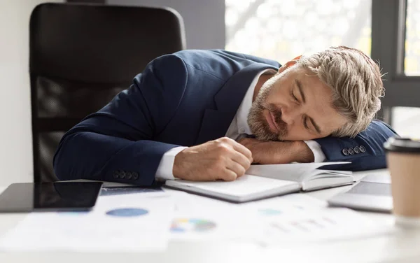 Overwerk Concept. Uitgeputte volwassen zakenman slapen op het werk in modern kantoor — Stockfoto