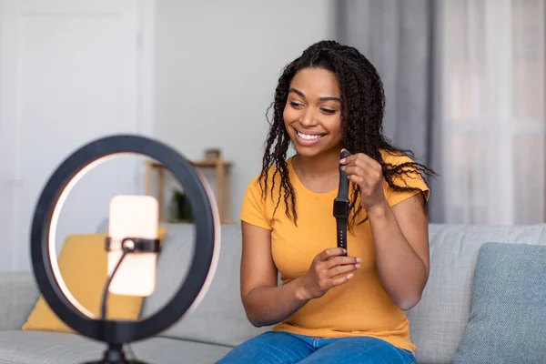 Bloger wanita yang bahagia merekam ulasan video model jam pintar baru, menggunakan lampu cincin dan ponsel di rumah — Stok Foto