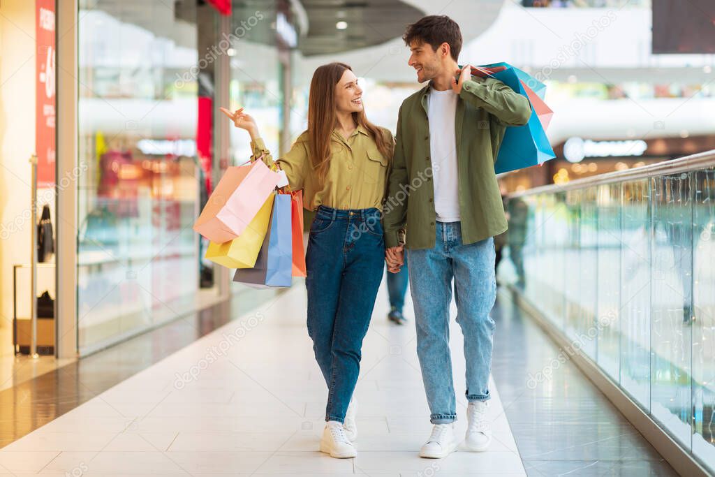 Customers Couple Shopping Walking Carrying Shopper Bags In Modern Mall
