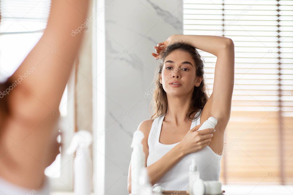 Attractive Woman Applying Antiperspirant Underarms For Sweat Protection In Bathroom