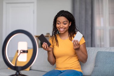 Genç Afrikalı Amerikalı blogcu çağdaş akıllı telefonların video incelemesini kaydediyor, cep telefonunun webcam kamerasıyla konuşuyor.