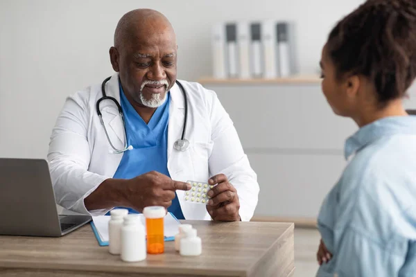 Experimentado médico negro mostrando píldoras a paciente femenino — Foto de Stock