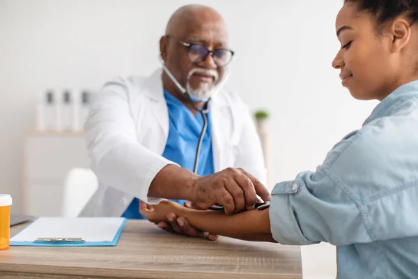 Black male doctor checking measuring pressure on patients hand — Stockfoto