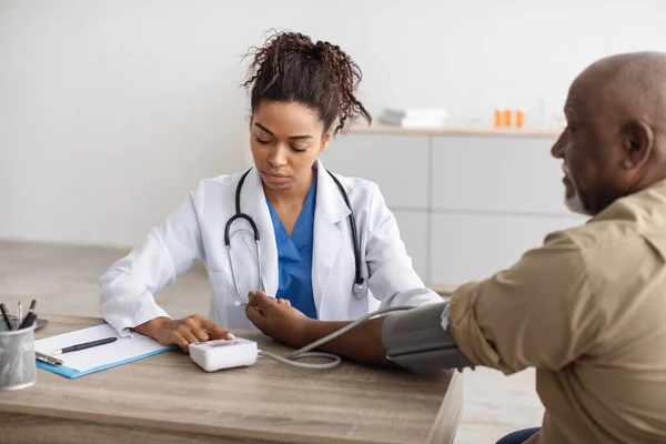 Чорна жінка-лікар перевіряє тиск на руку пацієнтам — стокове фото