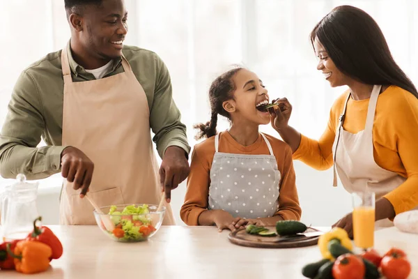Cheerful Black Family Preparing Dinner Making Fresh Salad In Kitchen