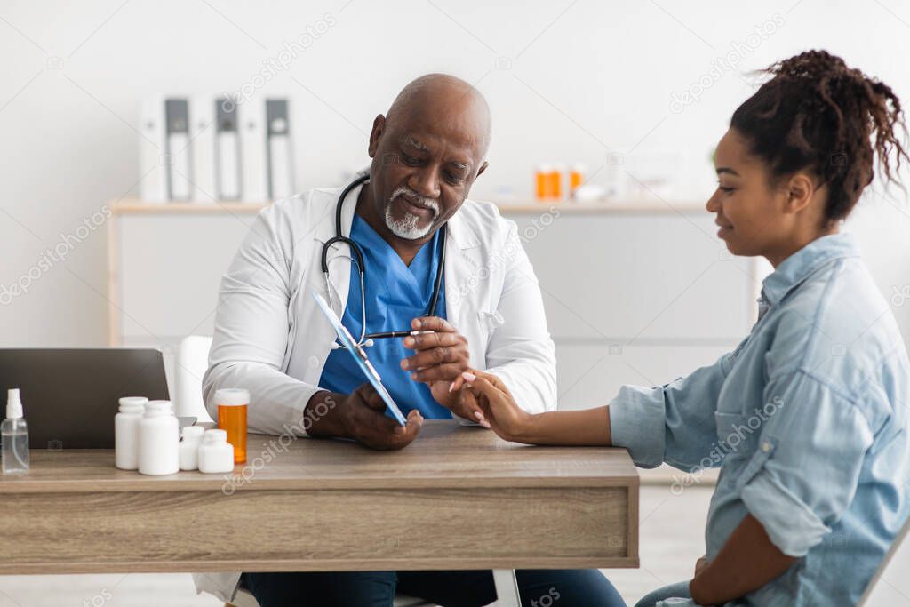 Experienced black doctor explaining treatment plan to female patient