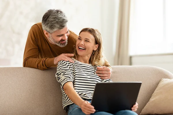 Радісні середнього віку подружжя використовуючи ноутбук Перегляд Інтернету вдома — стокове фото