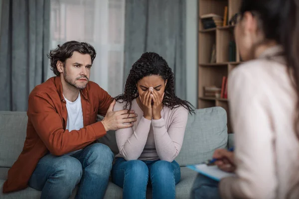 Trauriger europäischer Millennial-Mann tröstet weinende afrikanisch-amerikanische Frau auf Konsultation mit Psychologe — Stockfoto