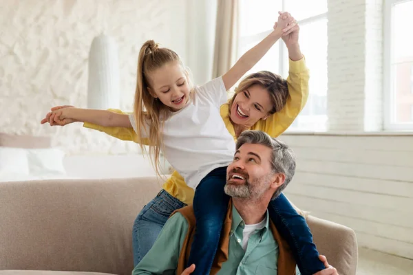Família feliz se divertindo, pai segurando filha nos ombros interior — Fotografia de Stock