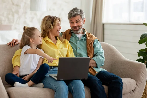 Famiglia allegra di tre utilizzando il computer portatile che naviga in Internet all'interno — Foto Stock