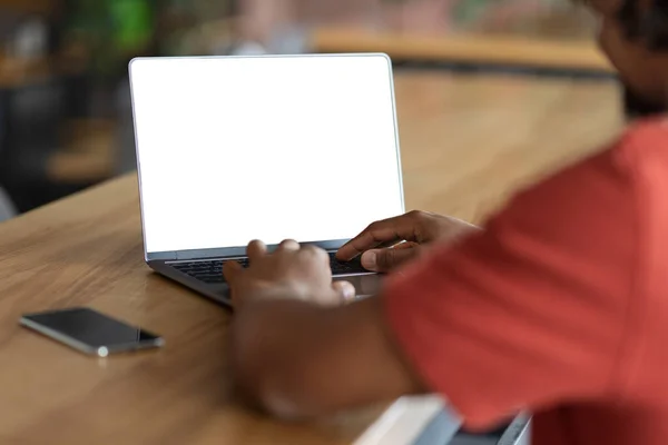 Cropped young african american guy blogger, student typing on computer keyboard with blank screen in cafe — Stock Photo, Image