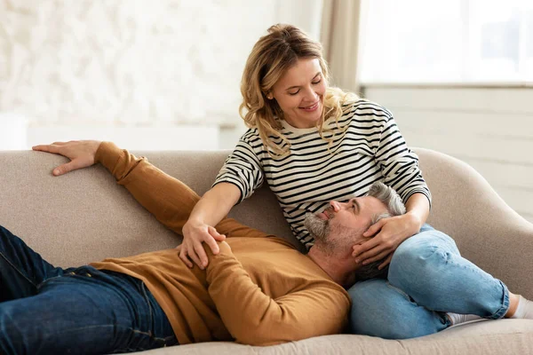 Amando casal de meia-idade relaxando no sofá em casa — Fotografia de Stock
